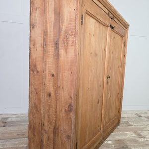 Antique Victorian pine cupboard with a stripped pine surface, twin doors, brass catches and bolt, and fixed internal shelving behind the doors.
