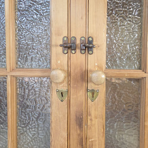 A generously proportioned antique pine glazed cupboard with a waxed surface and adjustable interior shelving. The full-length glazed doors are fitted with frosted glass for enclosed display.