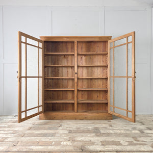 The antique pine glazed cupboard features a solid pine carcass, waxed surface, and frosted glass doors. Inside, four adjustable shelves make it suitable for a range of household or decorative uses.