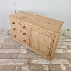 Cottage style pine storage unit with three drawers, a solid cupboard door, and turned wooden handles.
