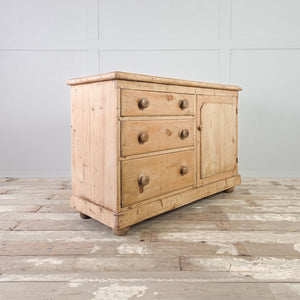 Country style pine dresser base with three drawers, a single cupboard, and rounded wooden bun feet.
