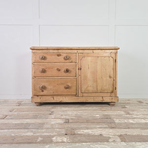 Victorian pine dresser base featuring three storage drawers and a traditional panelled cupboard door.
