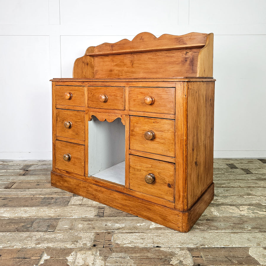 Antique English pine dresser base with seven drawers and a shelf.
