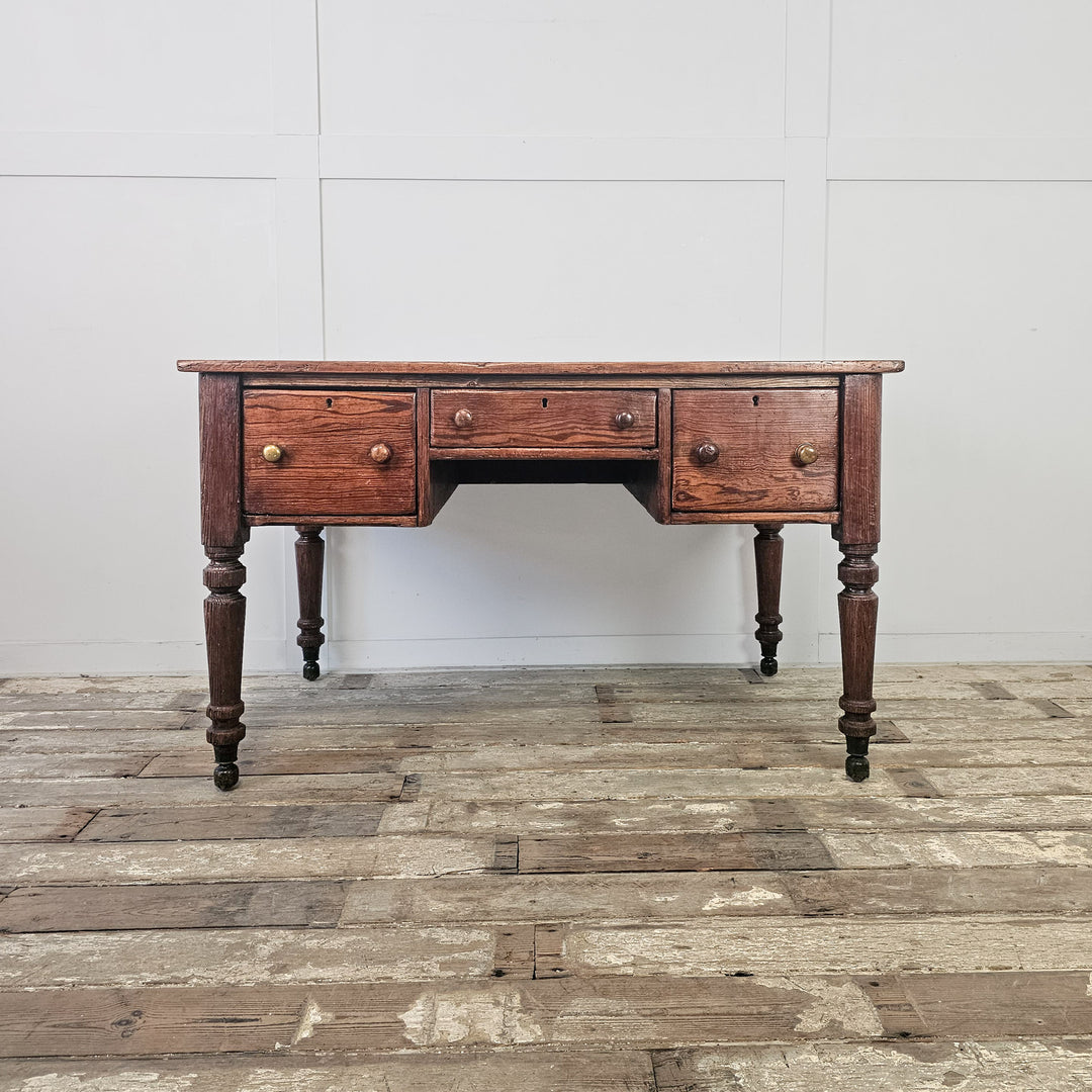 Antique pine farmhouse table with deep two-plank top, three drawers and turned legs on hidden brass castors

