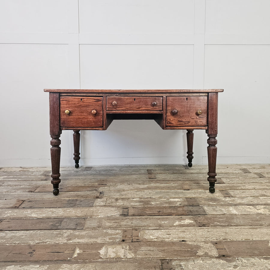 Antique pine farmhouse table with deep two-plank top, three drawers and turned legs on hidden brass castors

