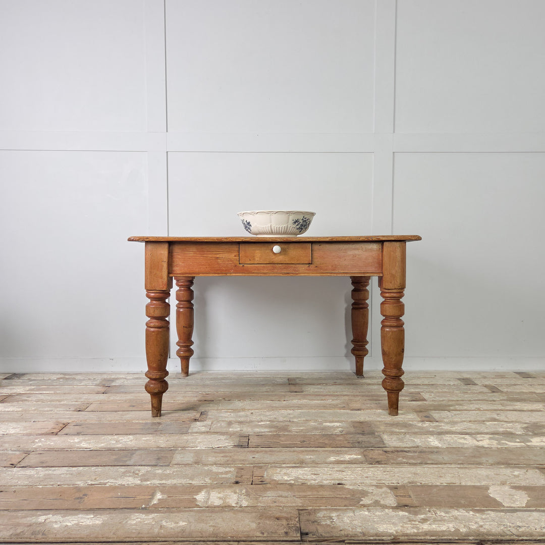 Victorian pine dining table with drawer for cutlery or table linens, shown on four solid turned legs with aged wear, original detailing, and a rich mellow pine tone.
