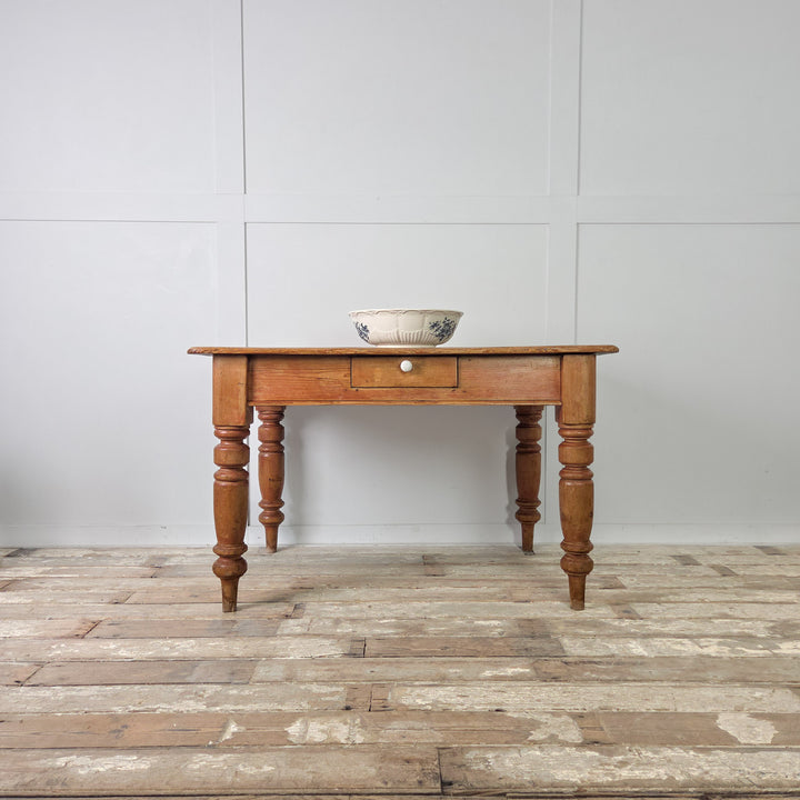 Victorian pine dining table with drawer for cutlery or table linens, shown on four solid turned legs with aged wear, original detailing, and a rich mellow pine tone.
