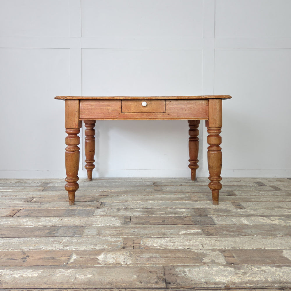 Late 19th century antique pine kitchen table featuring a worn plank top and ceramic drawer knob, finished in Fiddes Supreme Wax for a soft golden tone and authentic aged surface.
