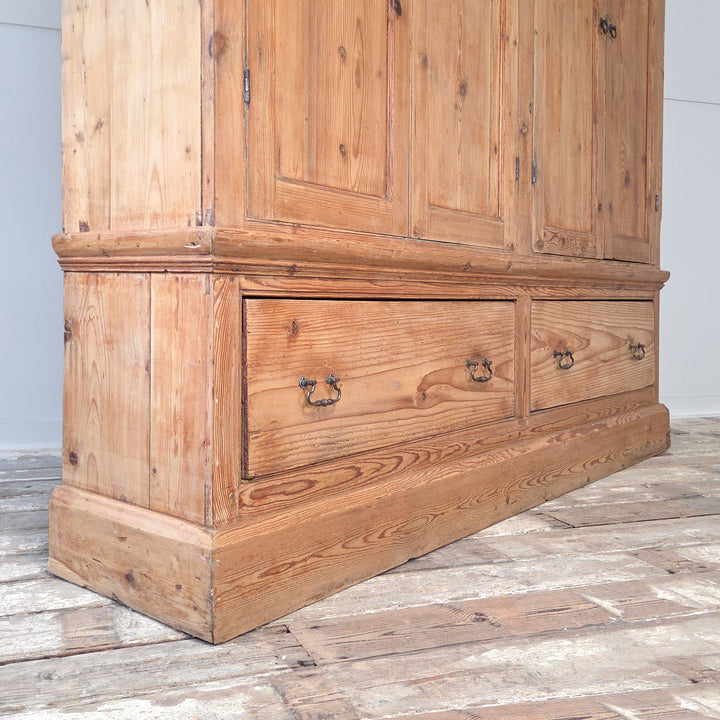• A 19th century Victorian English pine housekeeper’s cupboard with tall upper panelled doors, fixed shelving with blue painted finish, two deep base drawers, and a plinth base beneath a cornice top.
