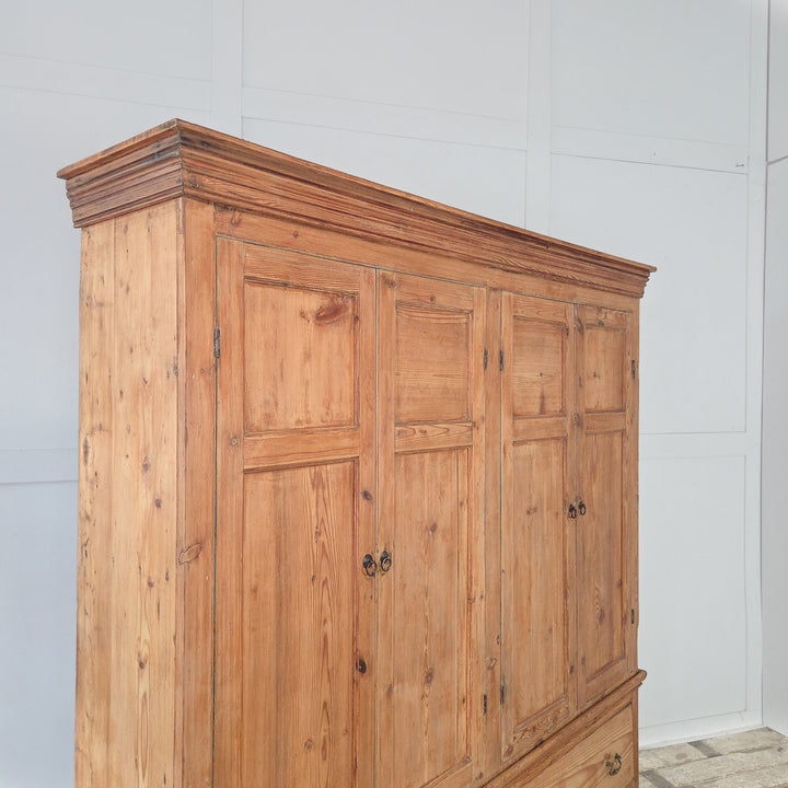 • An antique English pine housekeeper’s cupboard from the Victorian period, featuring upper cupboards with panelled doors and fixed shelving, and a lower section with two drawers, all raised on a plinth base.
