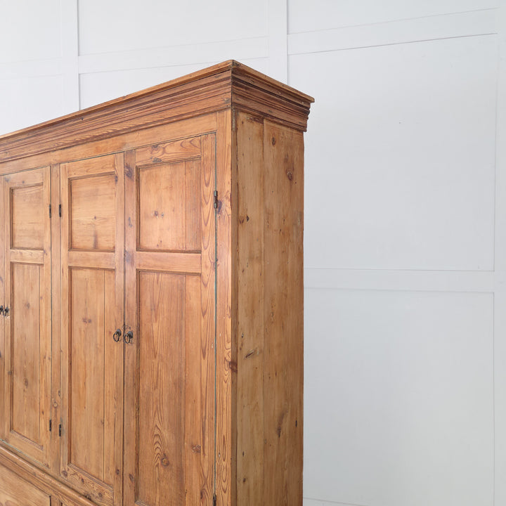The Victorian 19th century housekeeper’s cupboard is crafted in solid English pine with upper panelled cupboards, fixed blue-painted shelving, two large drawers with brass handles, and a plinth base with cornice.