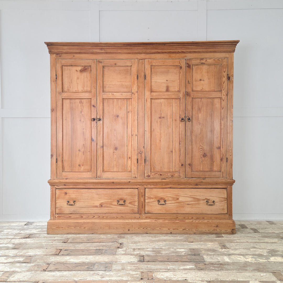 A generously scaled 19th century Victorian housekeeper’s cupboard in solid English pine, combining upper panelled cupboards with fixed shelving and a blue painted interior, and two lower drawers with brass handles