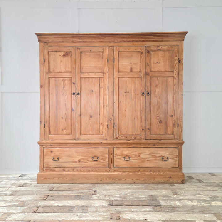 A generously scaled 19th century Victorian housekeeper’s cupboard in solid English pine, combining upper panelled cupboards with fixed shelving and a blue painted interior, and two lower drawers with brass handles