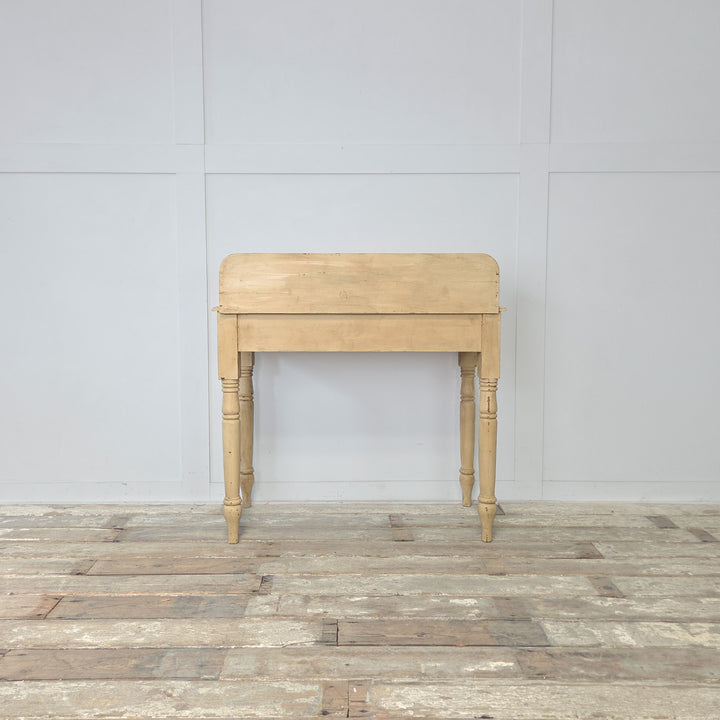 The antique painted pine washstand has a late 19th century Victorian design, with gallery back and shaped sides, turned legs joined by a lower shelf, and a pale yellow painted finish with contrasting pale blue trim, perfect for use as a console table in country or farmhouse-style homes.
