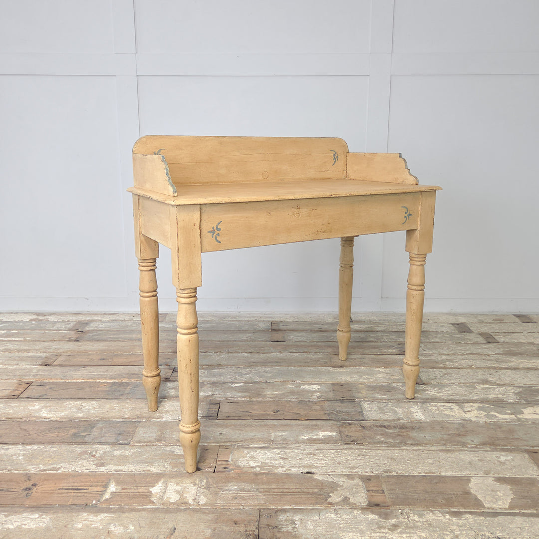A 19th century Victorian washstand in painted pine, with a gallery back featuring shaped sides, four turned legs connected by a lower shelf, and later pale yellow and pale blue painted detailing, suitable for use as an antique console table or farmhouse hallway piece.