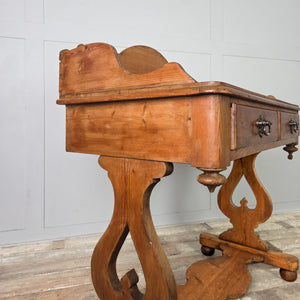 A country-style antique pine washstand from the late 19th century, with a shaped gallery back, two drawers and a lower shelf. The pine has a warm waxed finish and is raised on shaped supports terminating in ball feet.