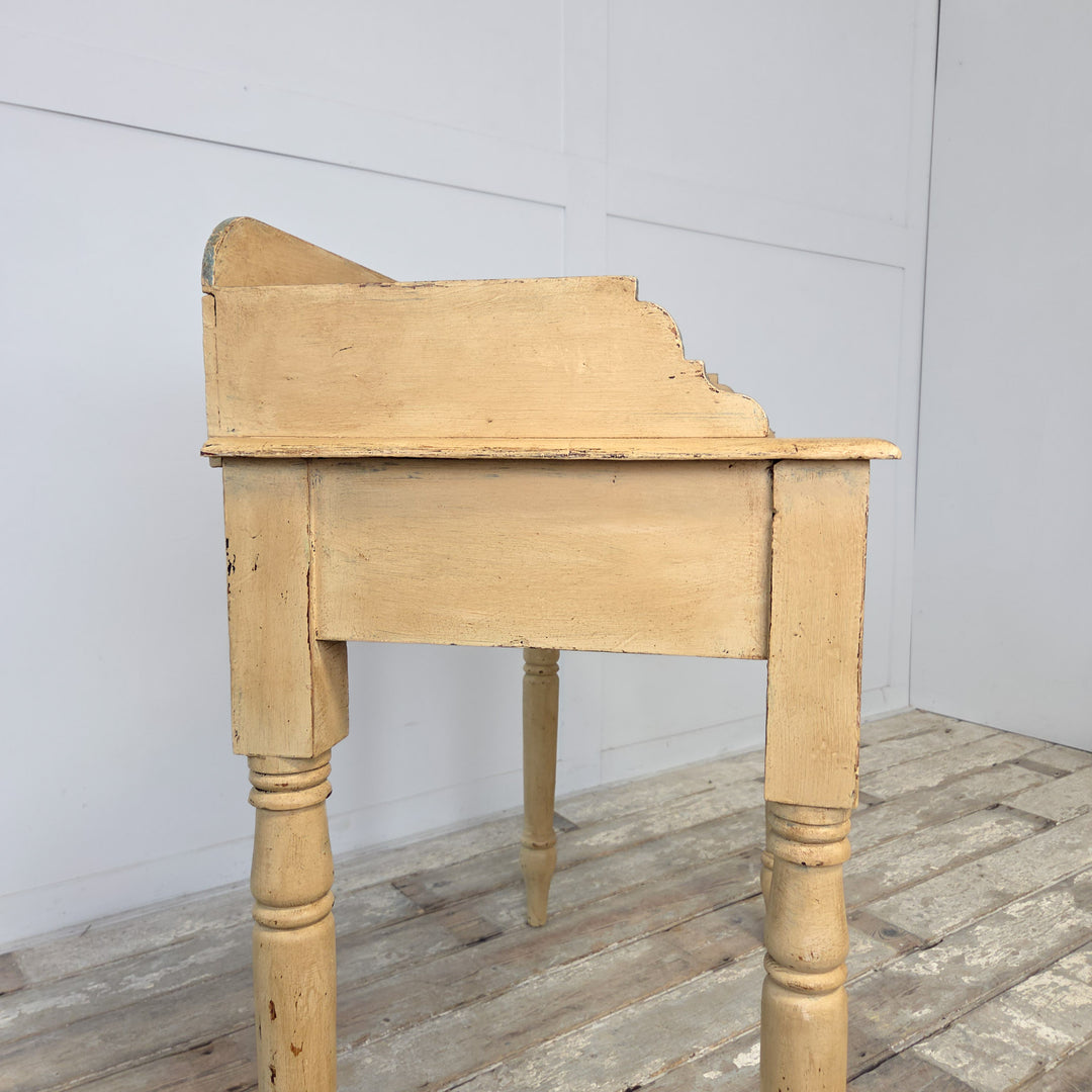 A Victorian washstand from the late 19th century, crafted in pine and later painted pale yellow with blue trim, featuring a shaped gallery back, four turned legs, and a lower shelf, ideal as a farmhouse console table or decorative piece for hallway or bedroom settings.