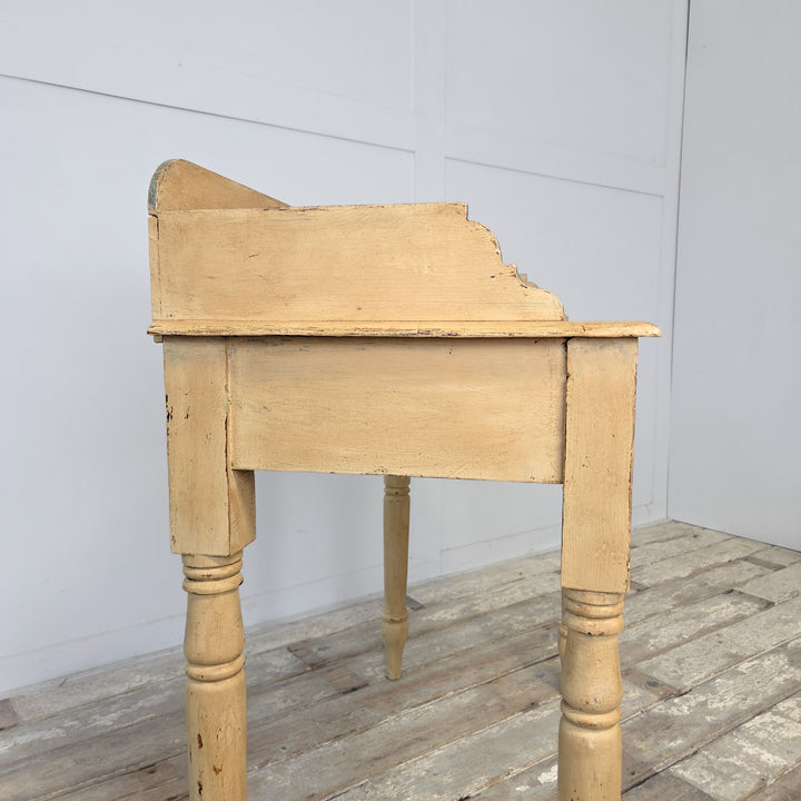 A Victorian washstand from the late 19th century, crafted in pine and later painted pale yellow with blue trim, featuring a shaped gallery back, four turned legs, and a lower shelf, ideal as a farmhouse console table or decorative piece for hallway or bedroom settings.