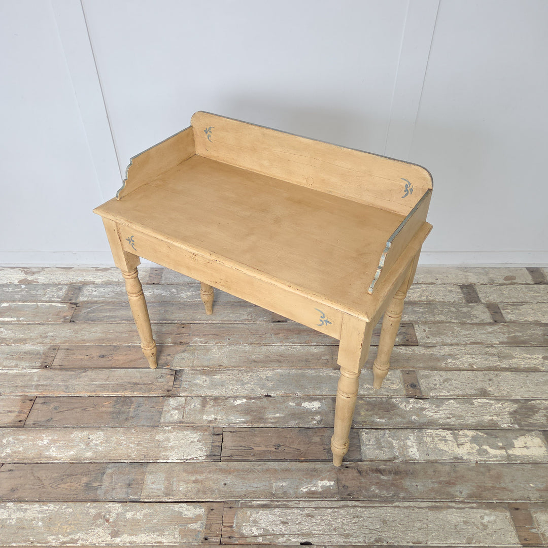 The late 19th century Victorian pine washstand has a shaped gallery back, turned legs, and a lower shelf, with a later painted finish in pale yellow and blue trim, making it a versatile antique console table or farmhouse-style accent for hallways or bedrooms.