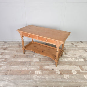 An antique Victorian pine washstand dating to the 19th century, with two drawers, a shaped lower shelf and turned legs, sealed in a clear wax to protect the light pine finish. Country and farmhouse in character, it works well as a console table in a hallway or as a dressing table in a bedroom.