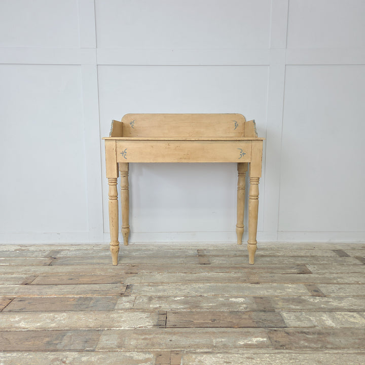 An antique painted pine console table from the late 19th century, originally a Victorian washstand, with gallery back, shaped sides, turned legs, lower shelf, and pale yellow and blue painted finish, adding character to a farmhouse hallway or bedroom.