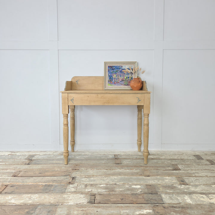 An antique Victorian painted pine washstand from the 19th century, later finished in pale yellow with pale blue trim, featuring a shaped gallery back, four turned legs, and a lower shelf, making a versatile farmhouse console table or decorative accent for hallway or bedroom interiors.