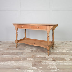 An antique pine washstand from the Victorian period with two drawers and a shaped lower shelf, raised on four turned legs and sealed in a clear wax finish. Rustic and country in character, this farmhouse piece is suitable for use as a washstand, console table or dressing table.