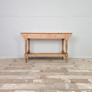 Victorian antique pine washstand from the 19th century with two drawers, a shaped lower shelf and four turned legs, finished in clear wax to protect the light pine surface. Rustic and country in character, this farmhouse piece works well as a console table or dressing table.