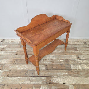 19th century Victorian pine washstand with gallery back, shaped scroll sides and lower shelf, supported by turned legs. A versatile antique piece that works as a farmhouse console or rustic side table, showcasing traditional pine craftsmanship and warm waxed patina.