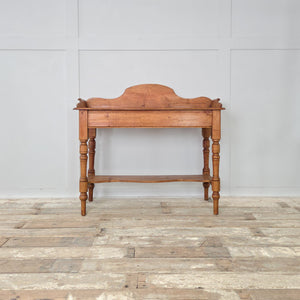 Antique Victorian pine washstand with decorative back, lower shelf and turned legs, finished in a wax polish. This versatile farmhouse style piece works as a console or rustic side table, adding antique character and 19th century craftsmanship to country homes or interiors.