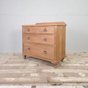 Farmhouse pine chest of drawers with rounded top corners and traditional glass hardware.
