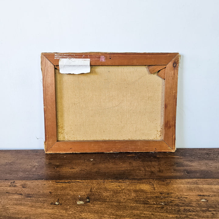 Rear view of a vintage floral oil painting canvas in a wooden frame, showing the aged texture and a paper note attached