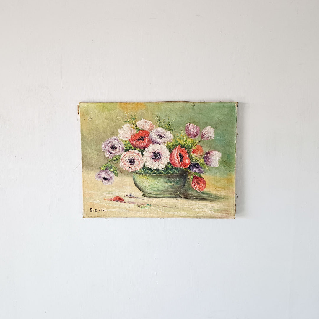 Vintage oil painting on canvas depicting a vibrant bouquet of flowers in a green bowl, signed by De Becker, displayed on a white wall