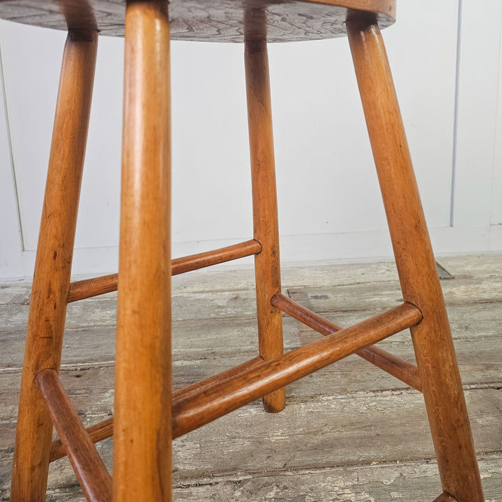 Antique elm stool with oval seat, ideal for vintage home decor.
