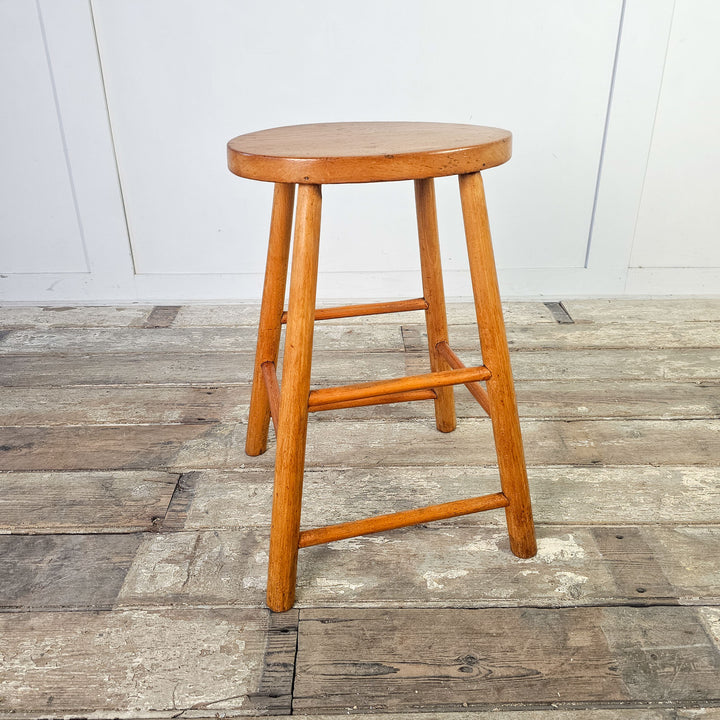 Mid-century elm seating stool with historical charm and oval top.
