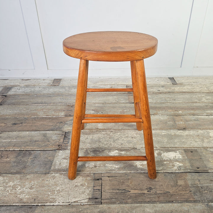 Mid-century elm wood stool with supportive stretchers and oval seat.
