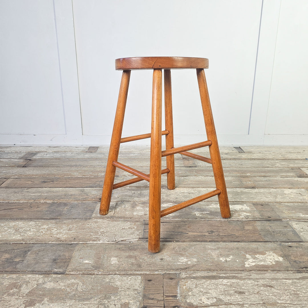 Vintage elm seating stool with supportive stretchers and oval seat.
