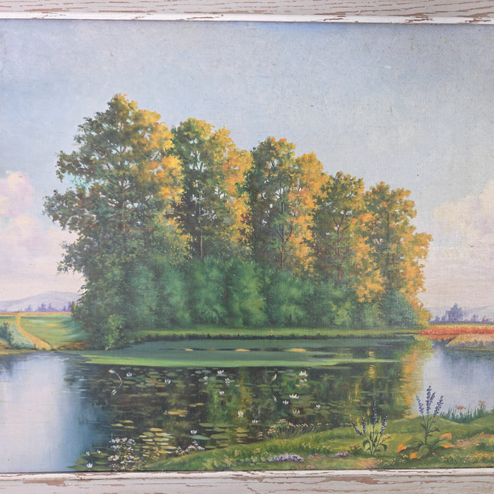 A 20th century vintage French landscape painting in oil on board, featuring a quiet rural view with a still pond, tall leafy trees, and surrounding meadow, held within a painted wooden frame with rustic character. An original artwork in earthy greens, blues, and natural tones, ready to display.