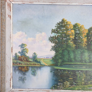A decorative 20th century vintage oil on board painting of the French countryside, showing a calm pond bordered by trees and fields, painted in natural greens, blues, and earthy hues. Displayed in a rustic painted wooden frame with gentle wear, this original artwork is ready to hang in the home.
