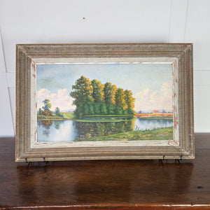Vintage oil painting on board of a French rural landscape, dating to the 20th century, depicting a still pond among tall trees and meadowland, rendered in natural greens and blues. Set within a rustic painted wooden frame with distressed finish, this original artwork is ready for wall display.