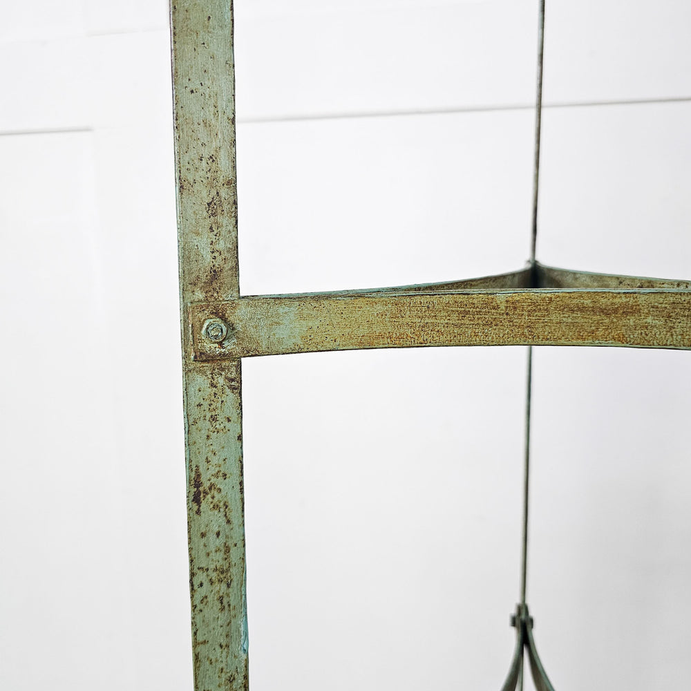 Vintage wrought iron pan stand with blue/green finish, perfect for cookware or plants.