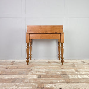A rustic pine dressing table with turned legs, two lower drawers and a gallery section arranged with pigeonholes, small drawers and a miniature cupboard. A neat cottage style design that provides simple, useful storage.