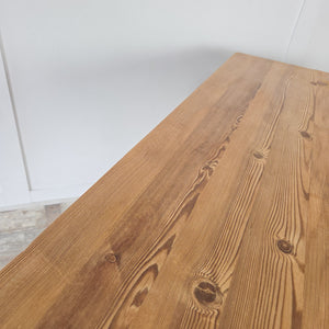 A rustic farmhouse pine trestle table, vintage mid-20th century, with stripped pine patina and thick rectangular top. Supported by a strong X-frame base and wax sealed for protection, this versatile table is ideal as a kitchen dining table, craft desk, or decorative console in traditional or modern homes.