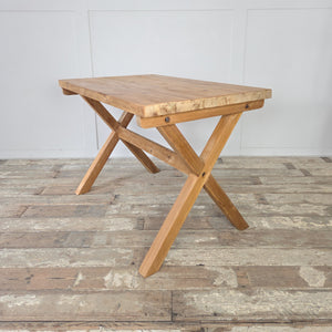A farmhouse style vintage pine table with a trestle design and distinctive X-frame base, finished in stripped pine and wax sealed. The rectangular top shows the natural grain, giving the piece character and durability. A practical vintage table ideal for use as a dining table, work desk, or console.
