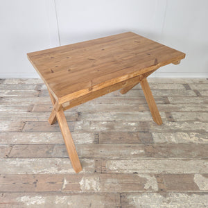 Rustic vintage pine trestle table with thick rectangular top and X-frame base. Stripped pine finish highlights the natural wood tone, sealed with clear wax for longevity. A farmhouse style table that can be styled as a dining table, craft desk, or console, adding versatility to interiors.