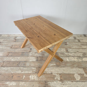 A vintage pine trestle table with farmhouse appeal, featuring a sturdy X-frame base and substantial pine top. The stripped finish highlights the wood grain and is sealed with wax to protect the surface. Ideal as a dining table for everyday use, or as a console or study desk within the home.