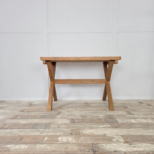 Mid-20th century vintage pine trestle table with distinctive X-frame support and thick rectangular top. Stripped and wax sealed for a natural patina, this farmhouse style table is a versatile piece, equally suited to kitchen dining, home office work, or as a rustic console in a hallway or living room.