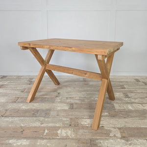 Farmhouse style vintage pine trestle table, featuring a thick rectangular top and a sturdy X-frame base. The stripped pine finish, wax sealed for protection, enhances the wood’s natural look. A vintage table perfect for use as a dining table, a work desk, or a console for rustic interiors.