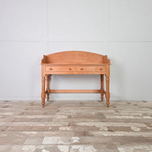 This vintage pine washstand features two drawers with matching wooden knobs and a shaped gallery back. Raised on four turned legs, it is a farmhouse-style piece suited to use as a dressing table in the bedroom or as a washstand in a bathroom, offering practical drawer storage.