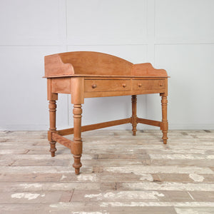 This vintage pine dressing table features two drawers, a shaped gallery back, and four turned legs. Originally a washstand form, it can be used as a dressing table in a bedroom or as a washstand in a bathroom, with practical drawer storage.